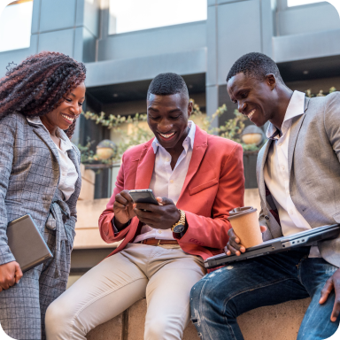 Three colleagues smiling together while looking at a phone